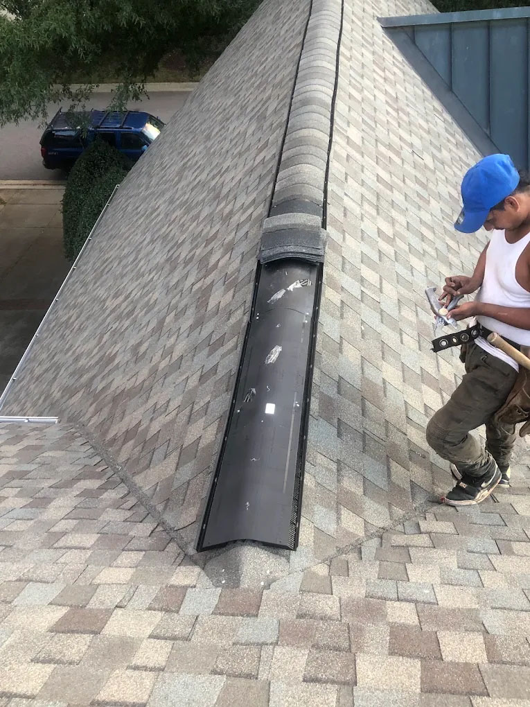 Roofer fastening shingles on a residential roof